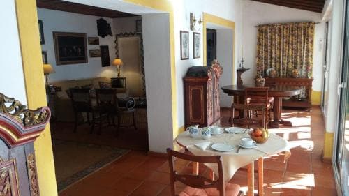 A cozy, sunlit Mediterranean-style villa interior features terracotta floors, vibrant yellow walls, and traditional furnishings, creating an inviting atmosphere ideal for a relaxing family vacation.