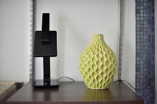 A cozy indoor setting features a modern black lamp and a textured yellow vase on a wooden shelf, ideal for travelers seeking home decor inspiration or minimalist room aesthetics.