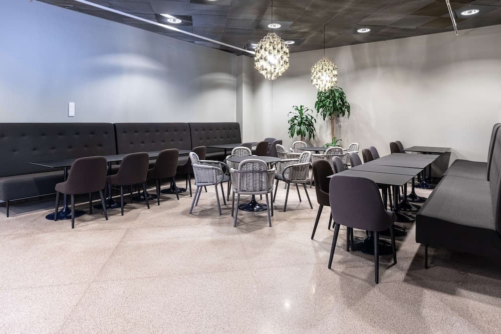 A modern, cozy lounge area features sleek tables, plush seating, and elegant chandeliers, creating an inviting atmosphere ideal for business travelers seeking a comfortable spot to relax or work.