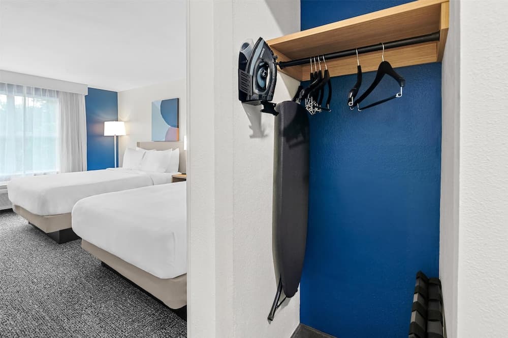 A cozy hotel room with two neatly made beds, blue accent walls, and an ironing station offers a comfortable stay for travelers seeking convenience and relaxation.