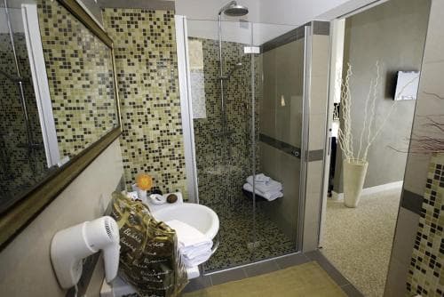 A modern bathroom with mosaic-tiled walls, a glass-enclosed shower, and a serene ambiance offers travelers a luxurious and relaxing retreat.