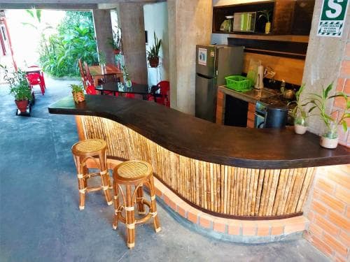 A cozy café with a bamboo bar, wooden stools, and lush greenery creates a welcoming atmosphere ideal for travelers seeking a relaxing spot to unwind and enjoy refreshments.
