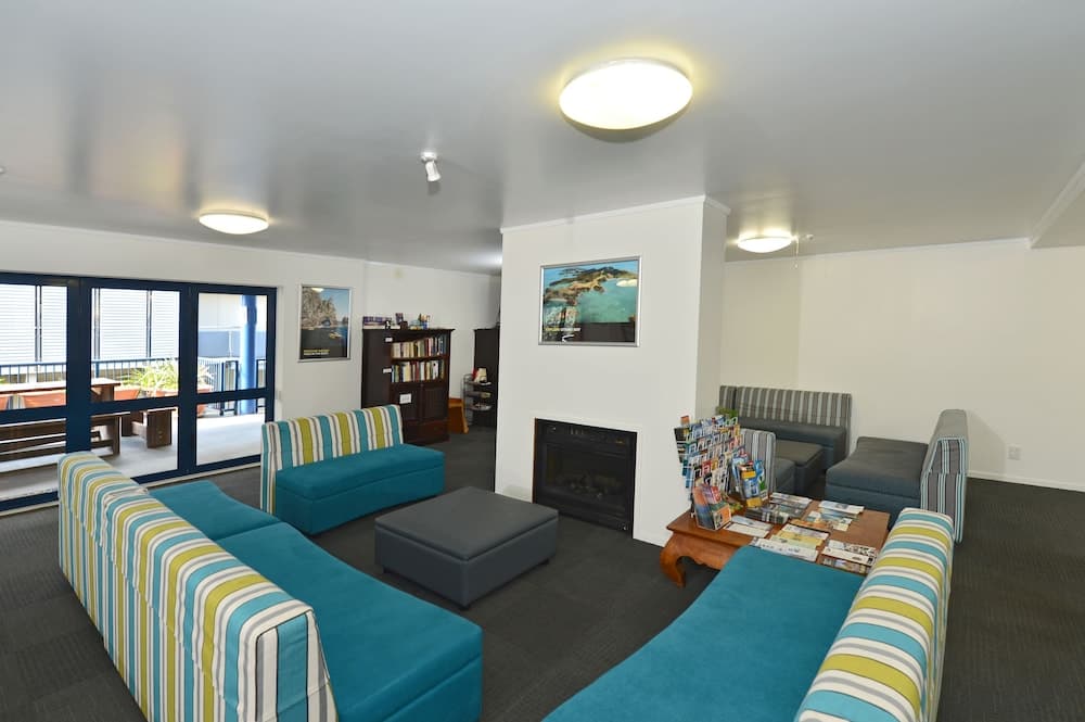 A cozy living room with striped sofas, a fireplace, bookshelves, and a balcony view offers a comfortable retreat for travelers seeking relaxation in a modern vacation rental.