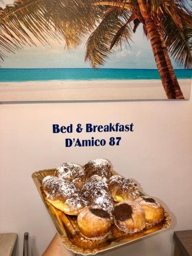 A cozy bed & breakfast scene featuring powdered pastries on a tray beneath a tropical beach mural, evoking a relaxed vacation vibe ideal for travelers seeking comfort and charm.