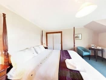 A cozy hotel room with a neatly made bed, soft lighting, and a comfortable armchair exudes a serene atmosphere, ideal for travelers seeking relaxation and rest.