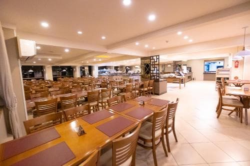 A warmly lit indoor dining area with wooden tables and chairs set for guests, featuring a cozy atmosphere ideal for travelers seeking a comfortable restaurant or hotel dining experience.