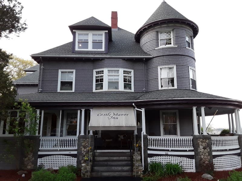 A charming Victorian-style inn with a turret and wraparound porch invites travelers to a cozy stay in Gloucester, MA, perfect for a serene coastal getaway.