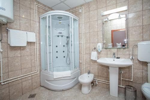 A cozy hotel bathroom features a modern shower cabin, tiled walls, and essential fixtures, ideal for travelers seeking comfort and cleanliness during their stay.