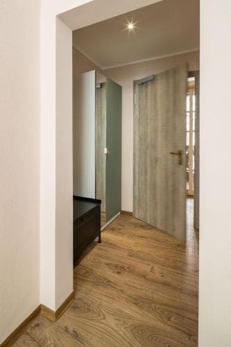 A cozy hotel hallway with wooden flooring, soft lighting, and a green curtain creates a warm and inviting atmosphere, ideal for travelers seeking comfort and tranquility during their stay.