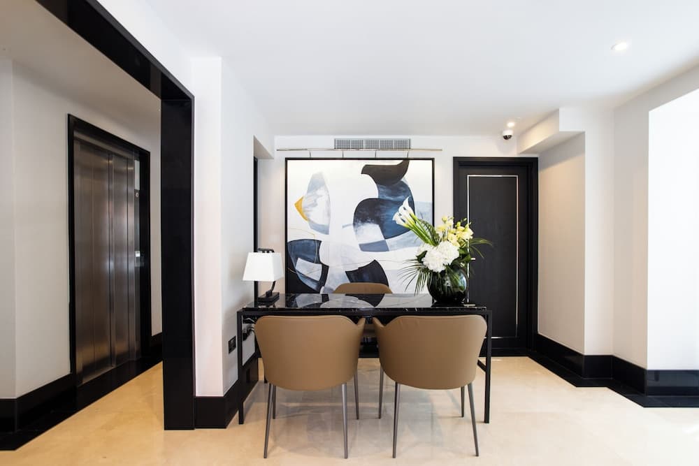 A modern hotel lobby features a sleek black and white color scheme with a minimalist desk setup, abstract artwork, and fresh flowers, creating an elegant atmosphere ideal for business travelers seeking a professional meeting space.