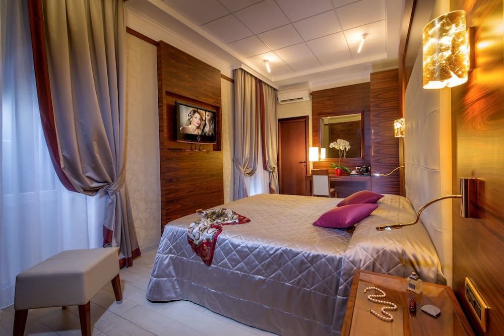 A cozy hotel room features a neatly made bed with purple accents, warm wooden paneling, ambient lighting, and elegant curtains, ideal for travelers seeking comfort and relaxation.