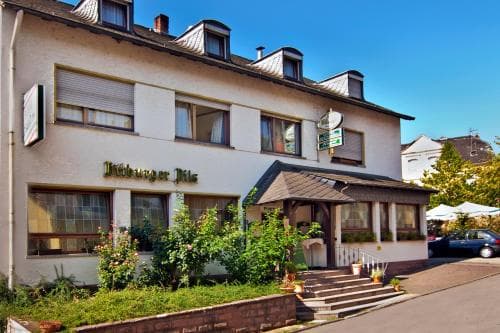 A charming European-style inn with a welcoming facade, lush greenery, and outdoor seating invites travelers seeking a cozy and picturesque accommodation experience.