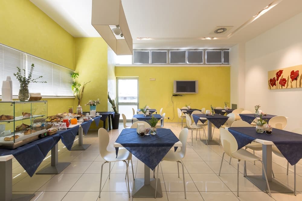 A bright, inviting breakfast room with yellow walls, navy blue tablecloths, white chairs, and a buffet display creates a cheerful dining atmosphere ideal for travelers seeking a comfortable morning meal.