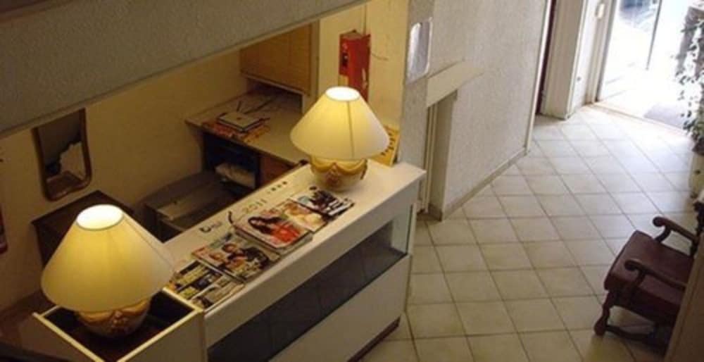 A cozy hotel lobby features warm lighting from table lamps, tiled floors, and a welcoming desk adorned with magazines, ideal for travelers seeking comfort and convenience.
