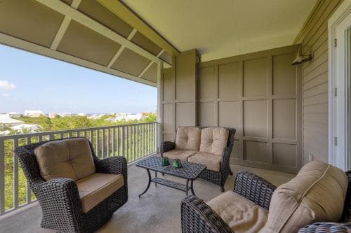 A cozy balcony with wicker furniture overlooks a scenic landscape, offering a tranquil retreat for travelers seeking relaxation in a vacation rental setting.
