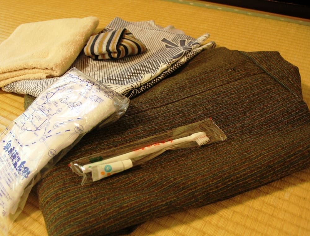 A cozy tatami room setup featuring neatly arranged bedding, towels, and toiletries, evokes a serene and traditional Japanese ryokan experience ideal for cultural immersion travelers.