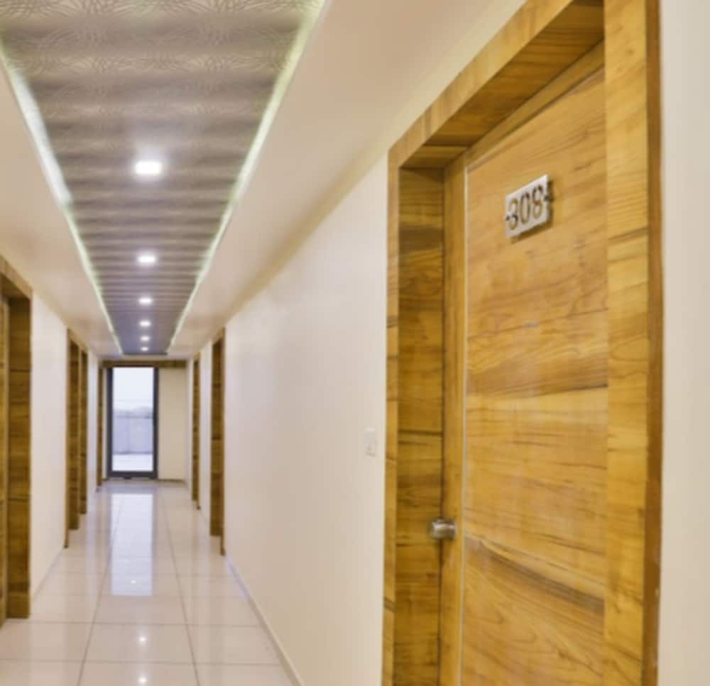A serene hotel corridor with wooden doors, tiled floors, and soft lighting creates a cozy atmosphere ideal for travelers seeking comfort and tranquility.