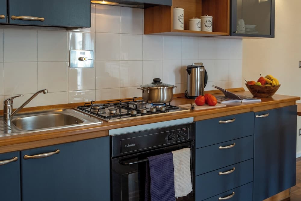 A cozy kitchen with blue cabinets, wooden countertops, and modern appliances creates a welcoming atmosphere ideal for travelers seeking a homey cooking experience.