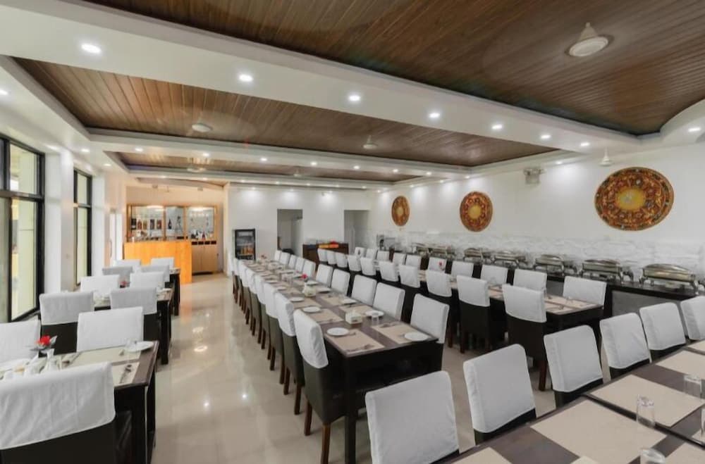 A spacious indoor dining area with neatly arranged tables and chairs under warm lighting, featuring decorative wall art and a buffet setup, ideal for travelers seeking a comfortable and inviting restaurant experience.