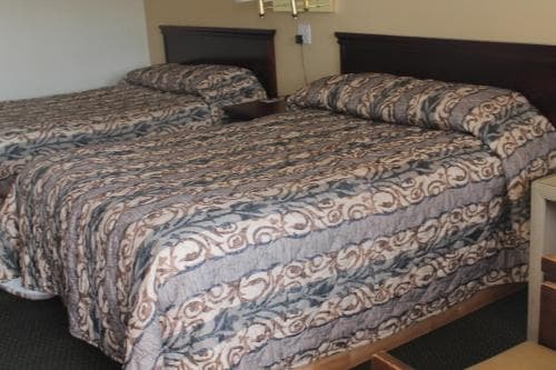 A cozy hotel room features two neatly made beds with patterned bedding, ideal for travelers seeking comfort and simplicity during their stay.