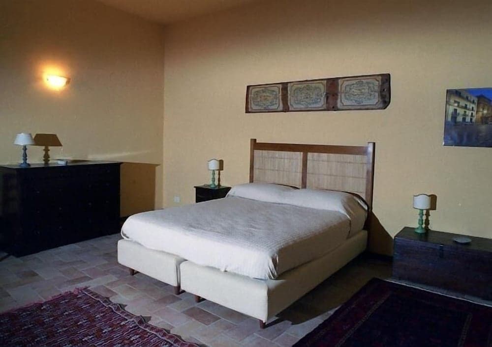 A cozy bedroom with terracotta flooring, wooden furniture, and warm lighting creates an inviting atmosphere ideal for travelers seeking comfort in a rustic retreat.