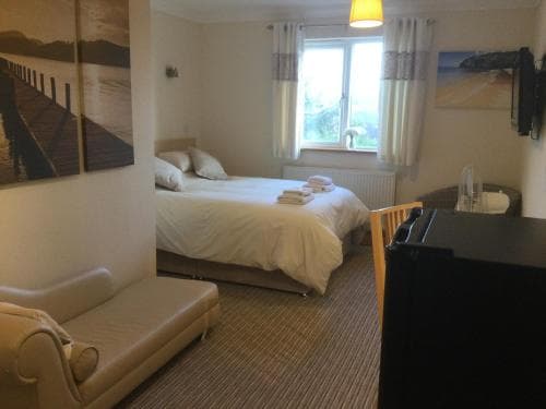 A cozy hotel room with a neatly made bed, soft lighting, and scenic artwork creates a welcoming atmosphere ideal for travelers seeking comfort and relaxation.