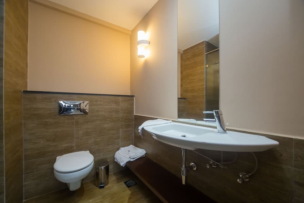 A cozy hotel bathroom features a modern toilet, sleek sink, warm lighting, and neatly folded towels, ideal for travelers seeking comfort and cleanliness.