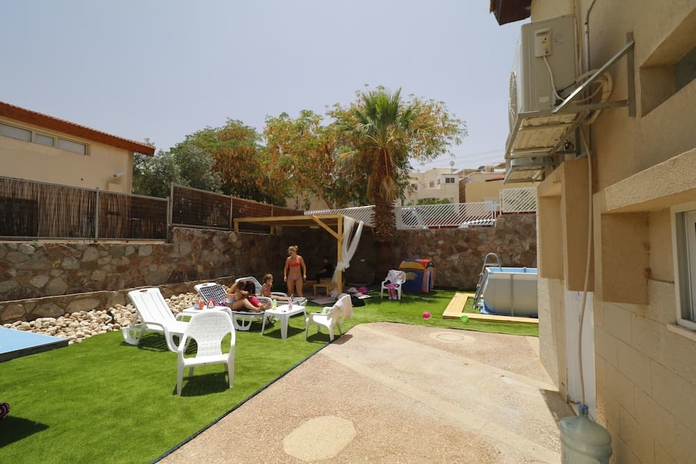A cozy backyard oasis features artificial turf, lounge chairs, a small pool, and palm trees, creating a relaxed family-friendly atmosphere ideal for vacation rentals.