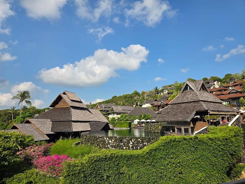 A serene tropical resort scene featuring traditional thatched-roof villas nestled among lush greenery under a bright blue sky, ideal for travelers seeking relaxation and luxury on Chaweng Beach, Koh Samui.