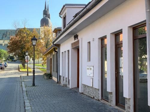 A serene cobblestone street lined with quaint shops and a towering church steeple in the background offers a picturesque setting for a leisurely stroll or cultural exploration.