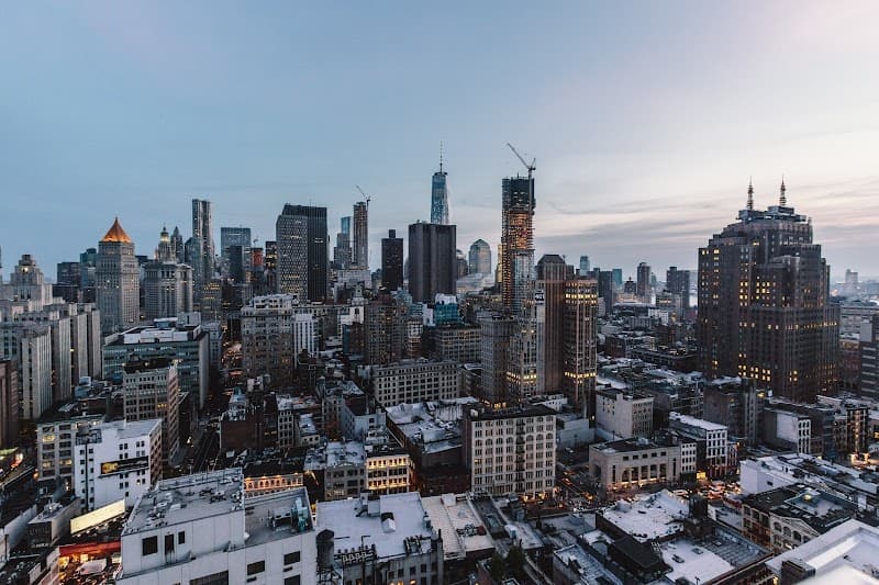 A stunning aerial view of New York City's urban skyline at dusk, featuring illuminated skyscrapers and rooftops, evokes a vibrant and bustling atmosphere ideal for cityscape enthusiasts and urban explorers seeking a unique perspective of the metropolis.