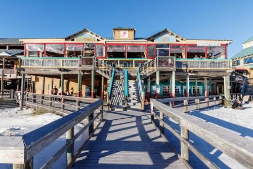 A vibrant boardwalk scene with colorful two-story buildings under a clear blue sky, ideal for leisurely strolls and exploring seaside attractions.