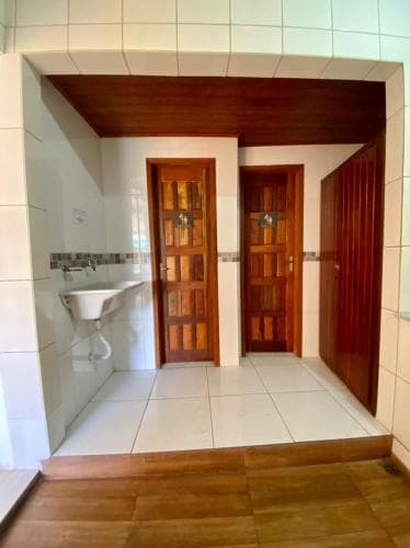 A cozy indoor hallway with tiled flooring, wooden doors, and a sink area creates a welcoming atmosphere ideal for travelers seeking comfortable accommodations.
