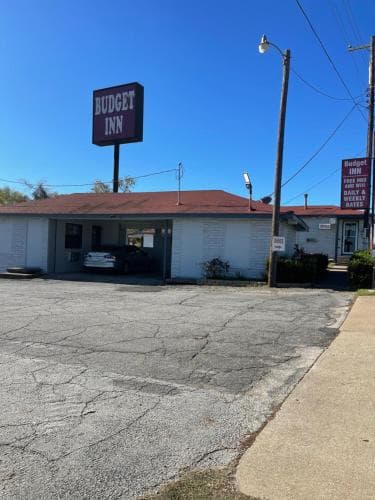 A budget-friendly motel with a prominent sign stands under a clear blue sky, offering travelers a simple accommodation option in a quiet roadside setting.