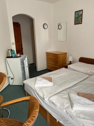 A cozy hotel room features a neatly made bed, wooden furniture, a small fridge, and a warm ambiance, ideal for travelers seeking comfort and simplicity.