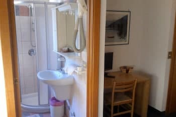 A cozy hotel room features a compact bathroom with a shower and sink, a wooden dining table with chairs, and a warm, inviting atmosphere ideal for travelers seeking comfort and convenience.