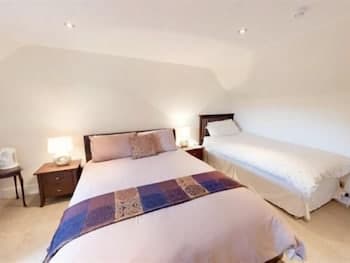 A cozy attic bedroom with slanted ceilings features two neatly made beds, warm lighting from bedside lamps, and a tranquil ambiance, ideal for travelers seeking a peaceful retreat.