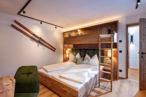 A cozy alpine lodge bedroom features rustic wooden decor, a bunk bed setup, and vintage skis on the wall, creating a warm and inviting atmosphere perfect for winter sports enthusiasts seeking a charming retreat.
