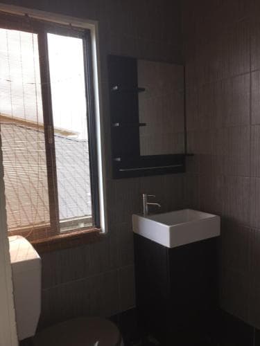 A cozy bathroom with tiled walls, a modern sink, and a window offering a view of rooftops, ideal for travelers seeking a clean and functional accommodation space.