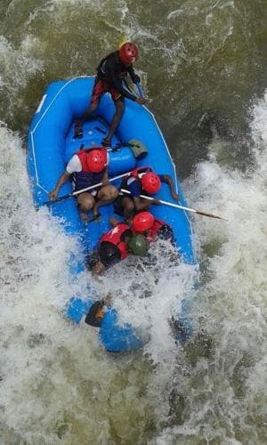 A group of adventurers navigates turbulent rapids in an inflatable raft, showcasing the thrill of whitewater rafting with vibrant safety gear and paddles, ideal for seekers of adrenaline-pumping outdoor activities.