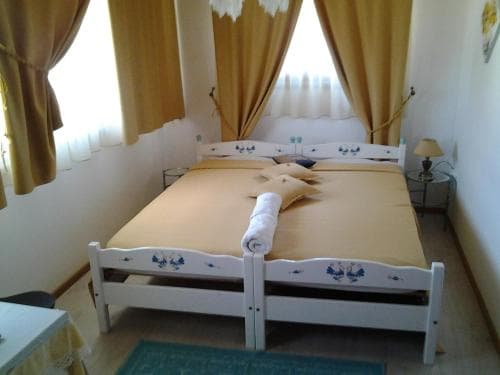 A cozy bedroom with a neatly made bed adorned with blue floral designs, warm yellow curtains, and soft lighting creates an inviting atmosphere, ideal for travelers seeking a comfortable and peaceful accommodation.