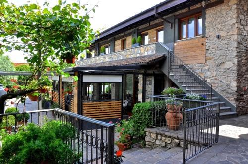 A charming stone building with lush greenery and vibrant potted plants creates a cozy, inviting atmosphere ideal for travelers seeking a quaint countryside retreat.