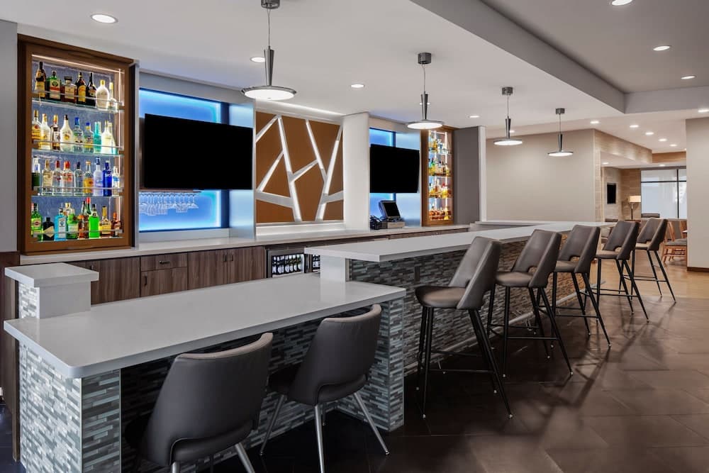 A modern bar area with sleek countertops, illuminated liquor shelves, and stylish barstools creates an inviting atmosphere perfect for social gatherings or business networking events.