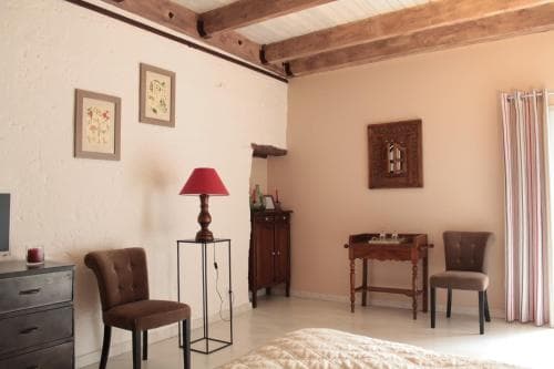 A cozy bedroom with rustic wooden beams, soft furnishings, and warm lighting creates an inviting atmosphere ideal for travelers seeking relaxation in a charming retreat.