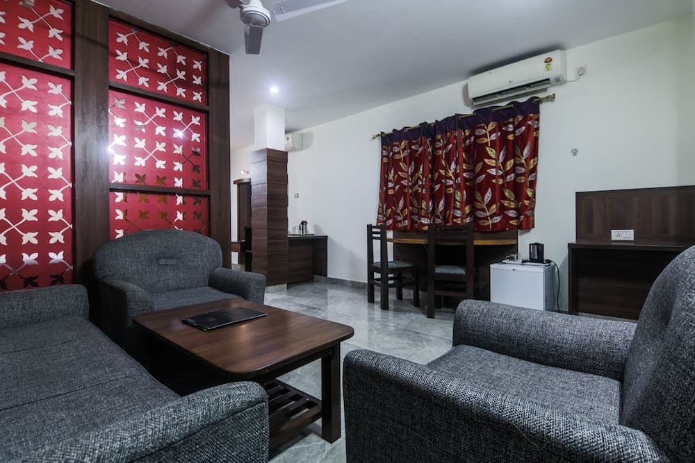 A cozy living room with gray sofas, a wooden coffee table, red patterned curtains, and modern amenities creates a welcoming atmosphere ideal for travelers seeking comfort in a compact apartment setting.