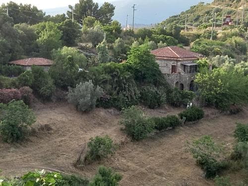 A serene rural landscape features stone houses nestled among lush greenery, ideal for tranquil retreats and nature lovers seeking a peaceful getaway.