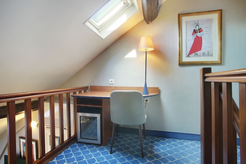 A cozy attic workspace features a wooden desk, modern chair, and skylight, creating an inviting atmosphere ideal for travelers seeking a quiet retreat for work or relaxation.
