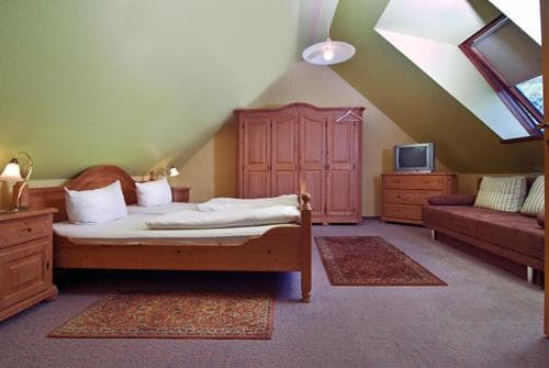 A cozy attic bedroom with sloped ceilings, wooden furniture, and warm lighting creates an inviting atmosphere, perfect for travelers seeking a quaint and comfortable stay.