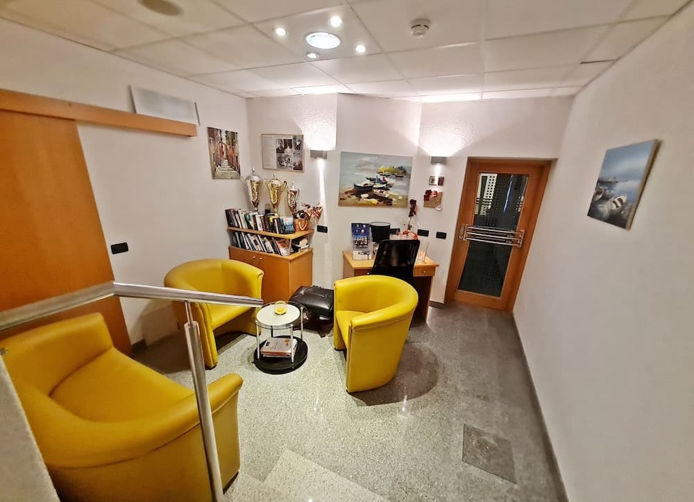 A cozy waiting area with vibrant yellow chairs, framed artwork, and trophies on display creates a welcoming atmosphere ideal for travelers seeking a comfortable spot to relax before their next adventure.