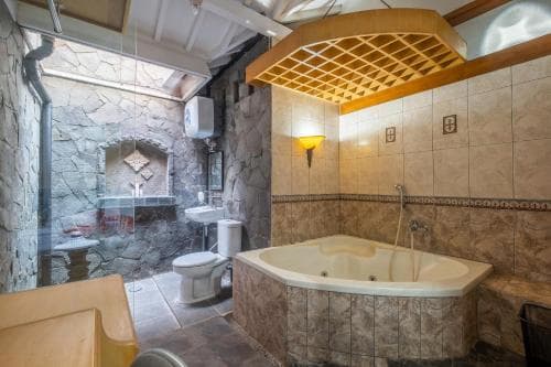 A cozy bathroom with stone walls, a luxurious bathtub, and warm lighting creates an inviting spa-like atmosphere perfect for relaxation during a travel getaway.